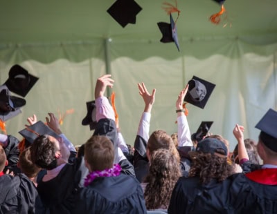 A group of graduates in caps and gowns celebrate under a tent, tossing their graduation caps into the air. The scene captures the joyful moment of achievement, mirroring the success found through ADHD treatment strategies, enhancing focus and celebrating personal milestones.