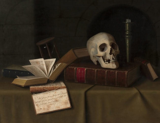 A still life featuring an open book, a skull, an hourglass, a letter, and a candle on a dark table with books. The setting gives a somber, contemplative atmosphere with a focus on themes of time and mortality.