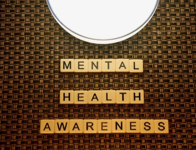 Small wooden tiles with letters on them that spell out Mental Health Awareness